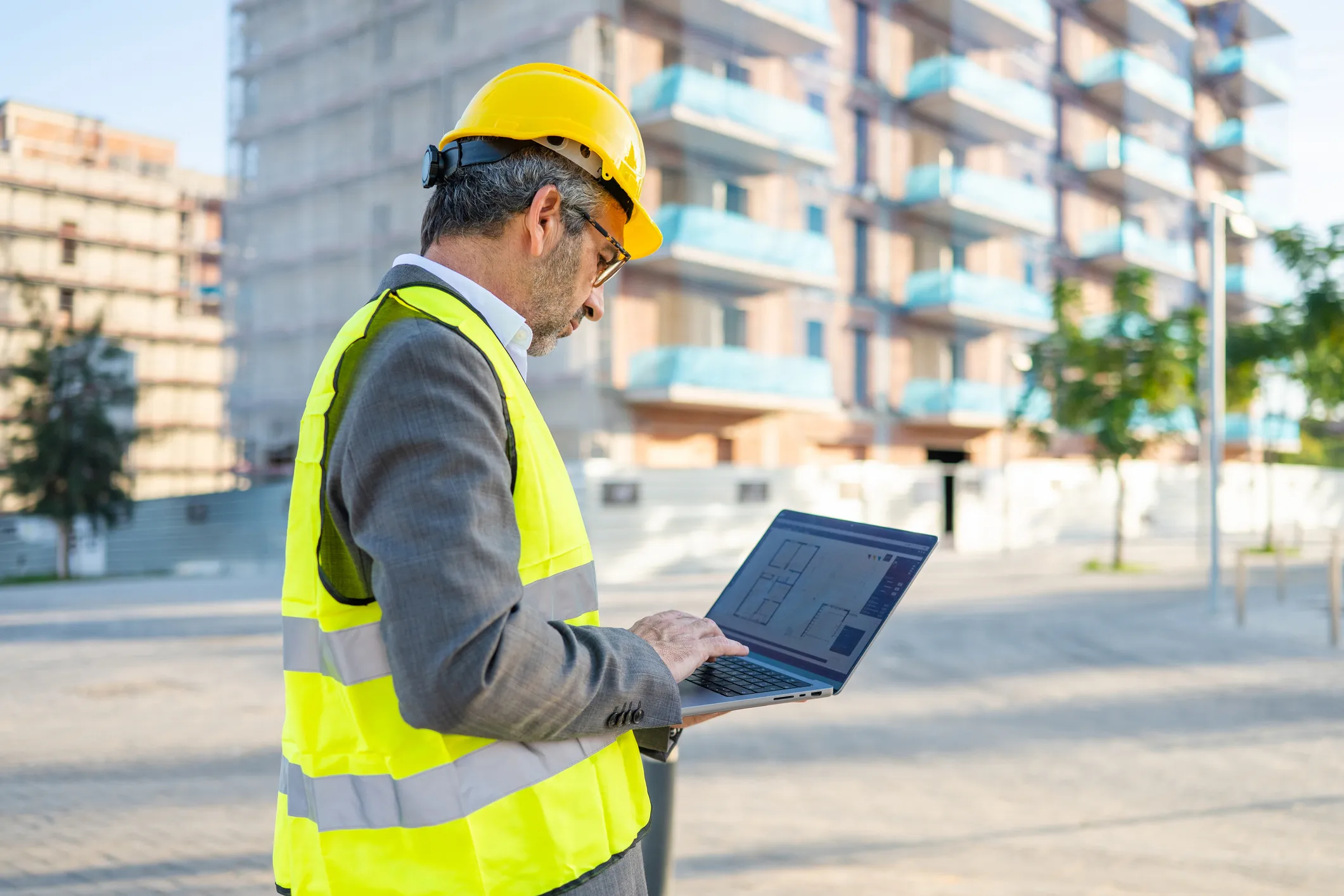 Mature adult engineer working on laptop at construction