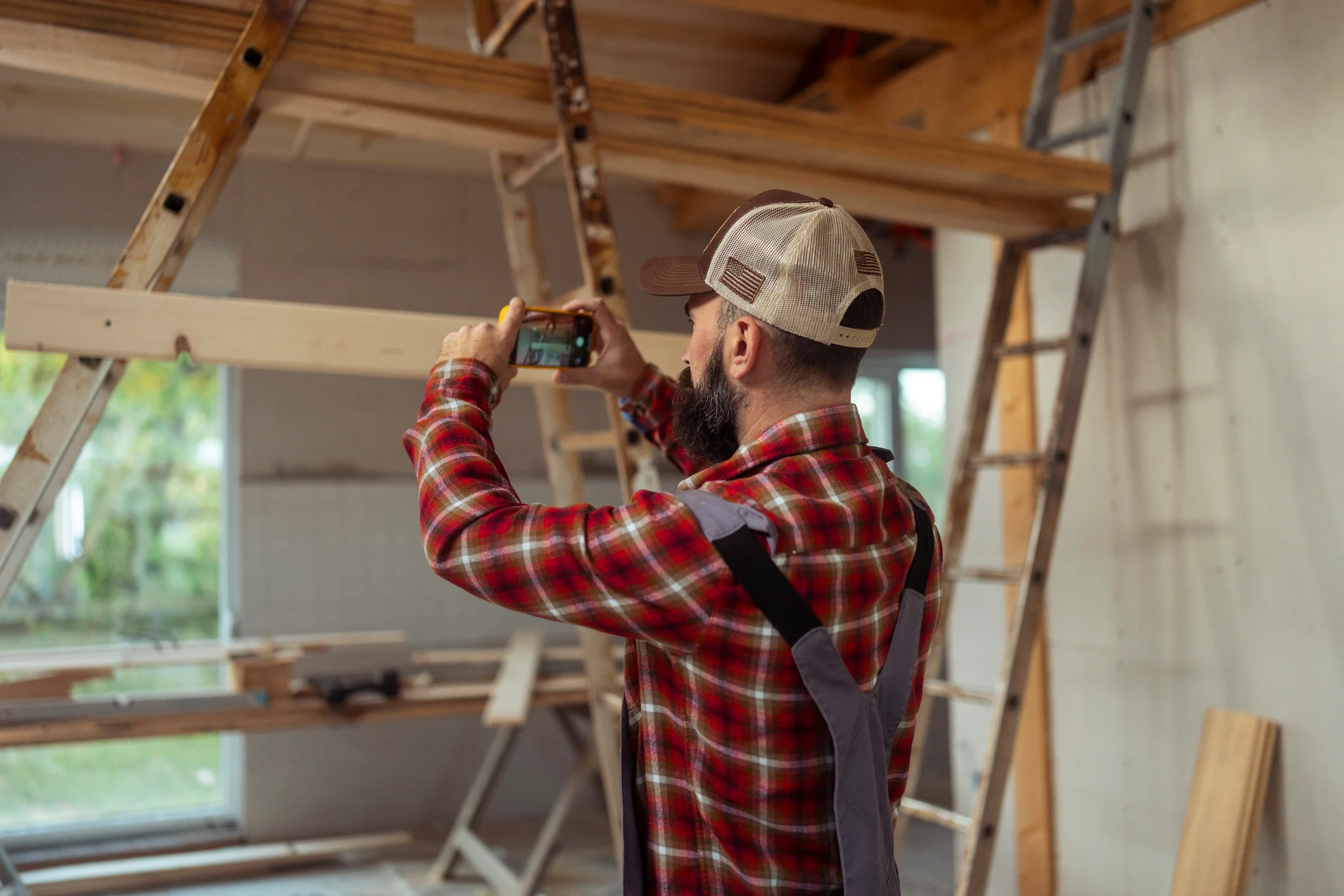 Construction Worker Taking Photos of Wooden House Under Construction Indoors